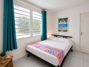 Un dormitorio con cama, cortinas, una ventana, una puerta y un cuadro colgado en la pared.