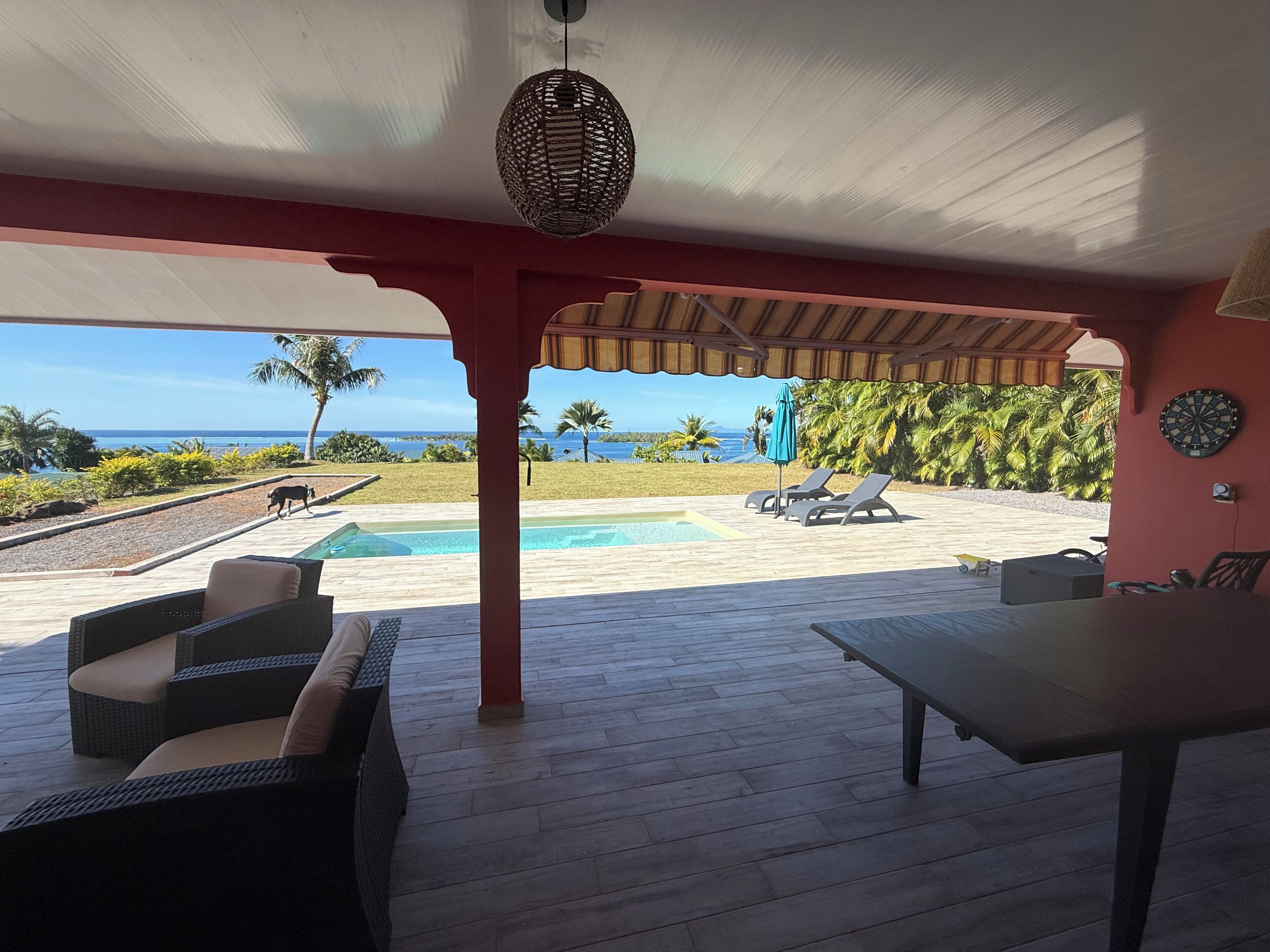 A covered outdoor area with a pool, lounge chairs, and a view of the ocean.