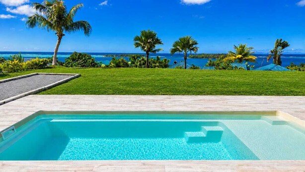 Una piscina rettangolare con acqua cristallina, circondata da un pontile in legno.