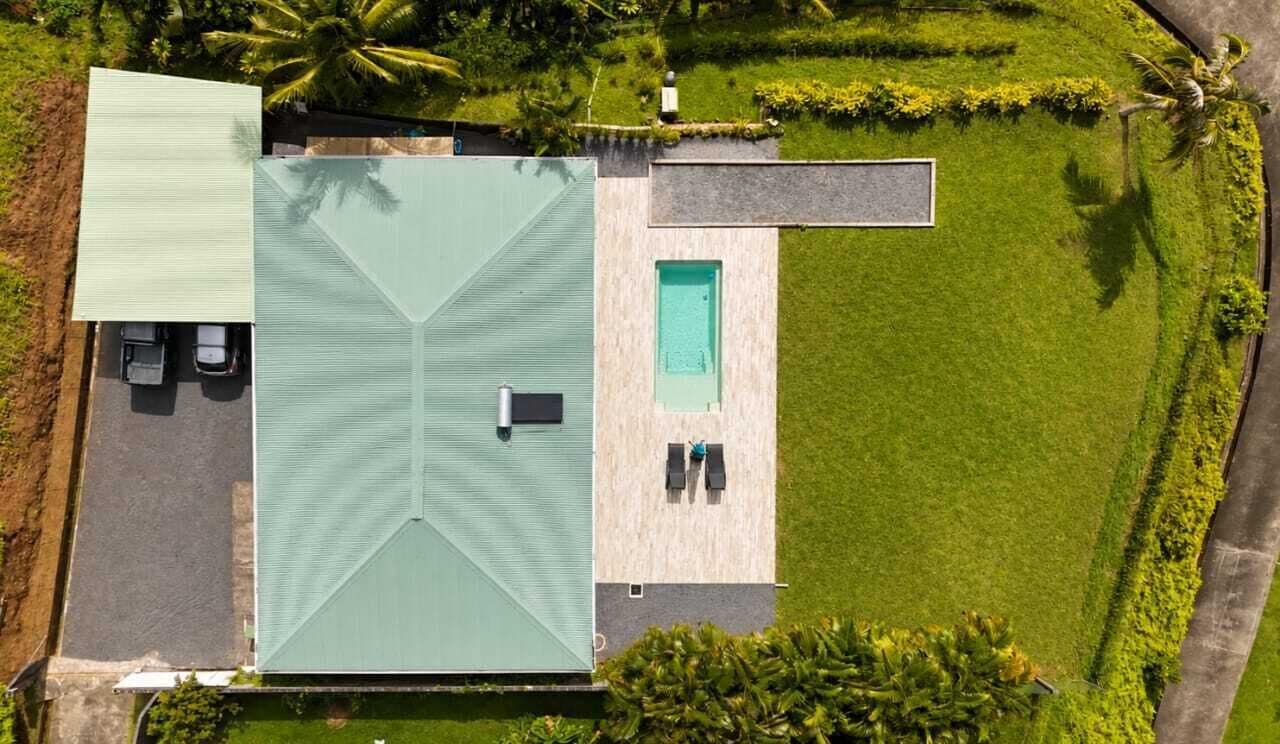 A rooftop with a swimming pool, a covered patio area, and a well-maintained lawn.