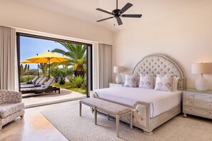 Ein Schlafzimmer mit einem großen Bett, einem Deckenventilator und Blick auf einen Pool und Palmen.
