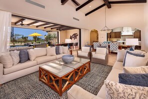 Amplia sala de estar con un sofá grande, sillones, una mesa de centro y vistas a una piscina y zona exterior.