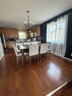 Una cocina moderna con armarios de madera, una mesa de comedor con sillas y un ventanal con vistas a árboles.