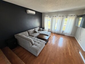 Una sala de estar con un sofá modular, una mesa de centro y un ventanal con cortinas.