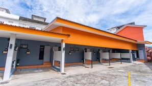 Un edificio con un espacio al aire libre techado, varias entradas y un estacionamiento.