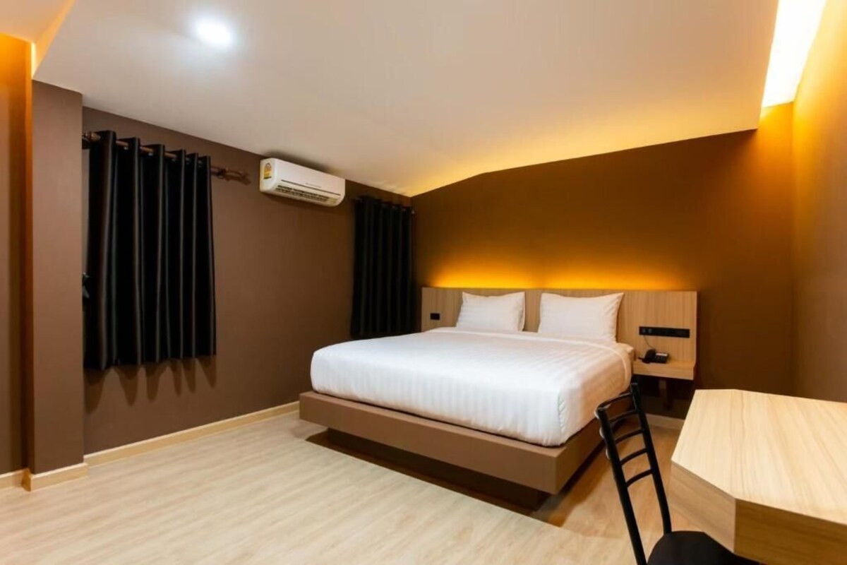 Una camera d'albergo moderna con un letto, un comodino e una scrivania con una sedia.