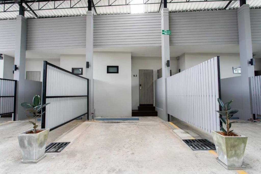 Un pasillo interior con una reja de metal, una escalera y plantas en macetas.