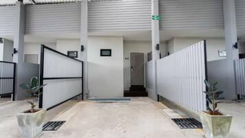 Un pasillo interior con una reja de metal, una escalera y plantas en macetas.