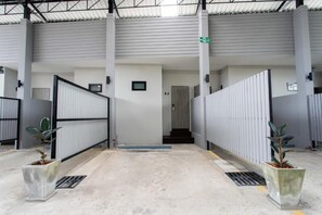 Un pasillo interior con una reja de metal, una escalera y plantas en macetas.