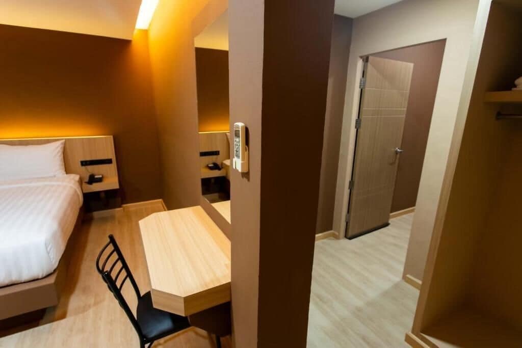 Et hotelværelse med seng, skrivebord, stol, sengebord og dør.