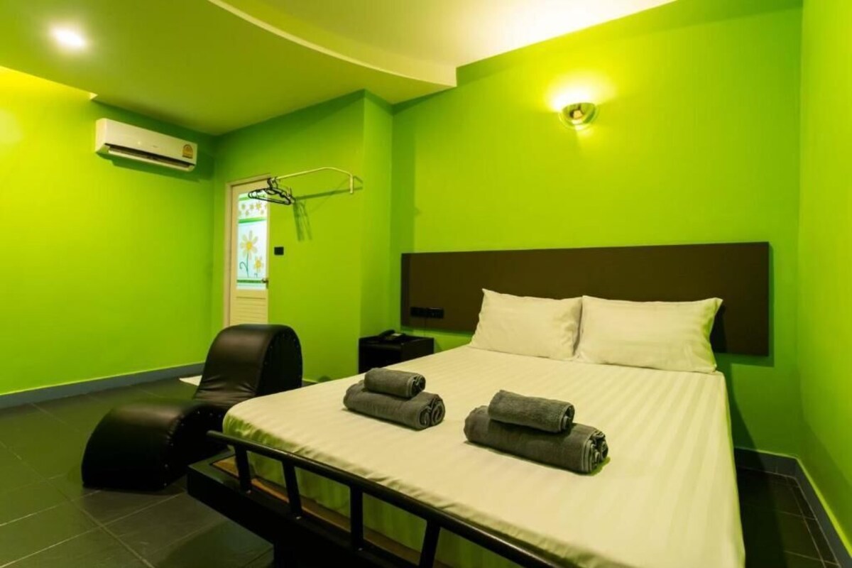 Una camera d'albergo con un letto, una sedia, un comodino e un condizionatore d'aria.