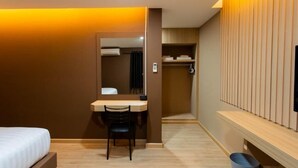 Una habitación de hotel con cama, escritorio, silla, espejo, armario y televisión.