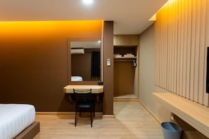 A hotel room with a bed, a desk, a chair, a mirror, a wardrobe, and a television.