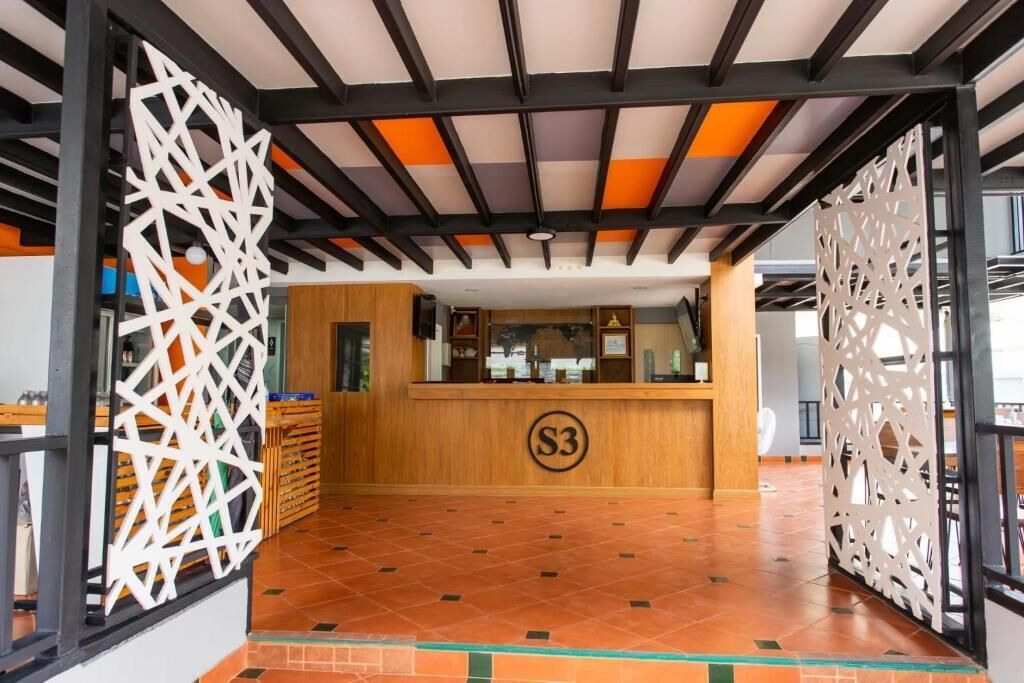 Un área de recepción con mostrador de madera, un letrero con el número 'S3' y paneles de celosía decorativos.