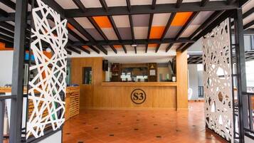 Un área de recepción con mostrador de madera, un letrero con el número 'S3' y paneles de celosía decorativos.