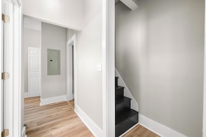 Ein Korridor mit Holzboden, weißen Wänden und einer schwarzen Treppe.