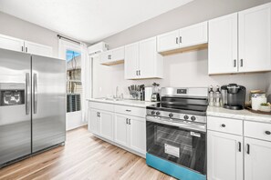 Eine moderne Küche mit weißen Schränken, Edelstahlgeräten und Holzboden.
