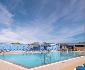 A swimming pool with lounge chairs and a building in the background. - Holiday Caravan Sleeps 4 with Parking (Paignton)