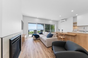Una sala de estar moderna con un sofá, un comedor con mesa y una cocina con mostrador.