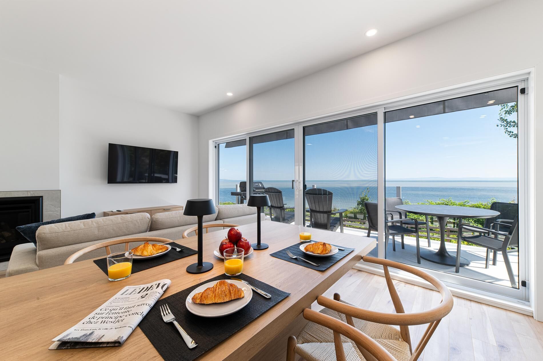 Un espace repas moderne avec vue sur la mer, un canapé et un téléviseur à écran plat.