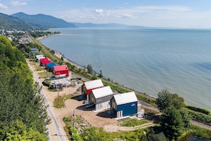 A coastal area with a row of buildings along the shore, a road, and a body of water.