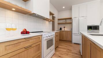 A modern kitchen with white cabinetry, a white countertop, wooden flooring, and a built-in oven.