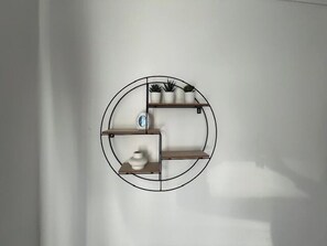 A circular wall-mounted shelf with various items including a vase, a small plant, and a decorative object. - Central Wimbledon Apartment with 2 Bedrooms, Free Parking, Fast WIFI (London)