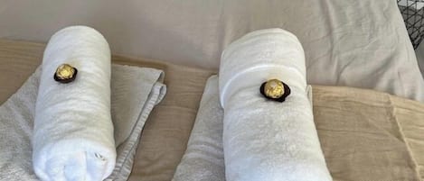 A bed with two neatly folded towels placed on a beige bedspread.