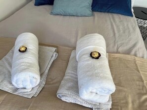 Un lit avec deux serviettes soigneusement pliées, posées sur un couvre-lit beige.