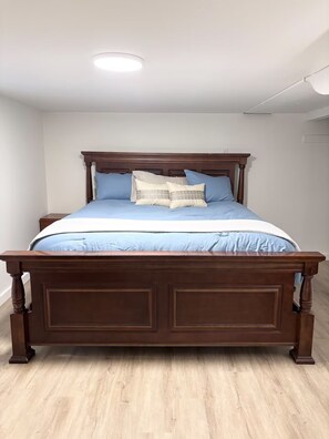 Une chambre à coucher avec un lit en bois, un plafond blanc et un luminaire.