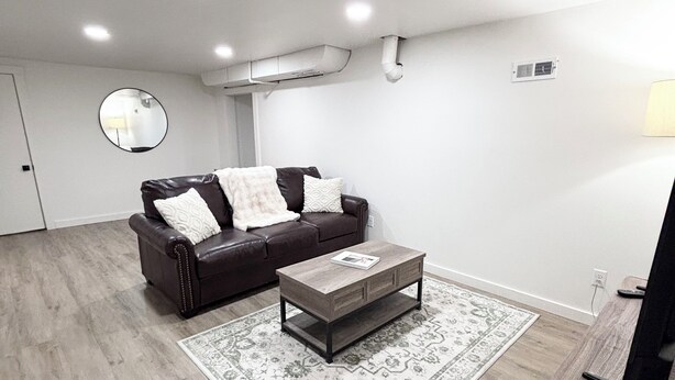 A modern living room with a leather sofa, a wooden coffee table, and a patterned rug. - Spacious & Cozy Suite Getaway in KC Area · No Stairs (Blue Springs)