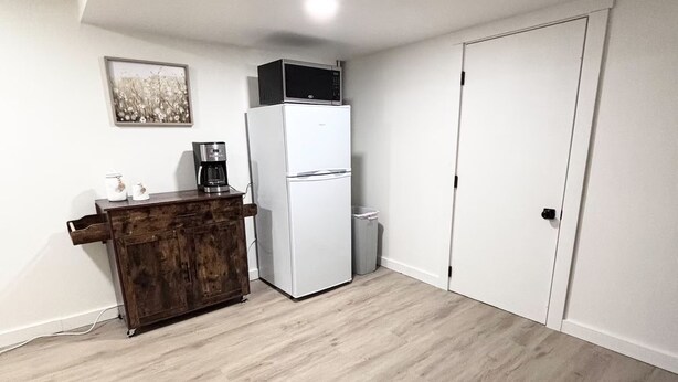 A compact kitchen with a refrigerator, microwave, coffee maker, and a small cabinet. - Spacious & Cozy Suite Getaway in KC Area · No Stairs (Blue Springs)