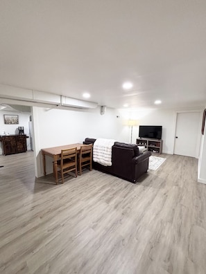 Amplia sala de estar con mesa de comedor, sofá, televisor y cafetera.