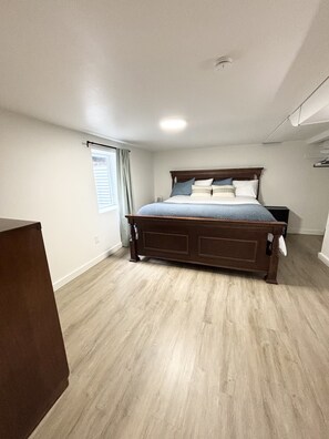 Une chambre avec un grand lit, une fenêtre avec des rideaux et un plancher en bois.
