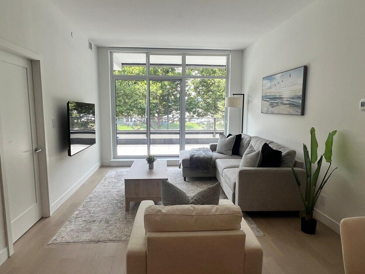 A modern living room with a sofa, a coffee table, and a TV mounted on the wall.