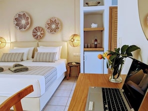 A bedroom with a bed, bedside lamps, a laptop on a wooden table, and decorative wall art. - Villa Karina Near Achladies Beach (Skiathos)