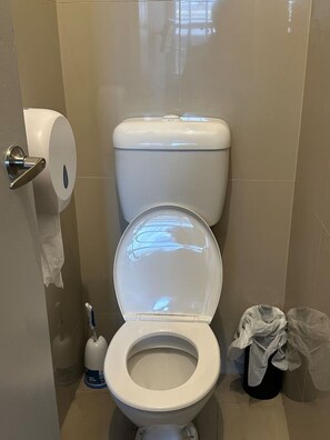 A toilet with a paper towel dispenser, a bidet, and a trash bin in a bathroom with beige tiles. - 5 mins to Central Sydney
Lord Raglan Hotel (Alexandria)