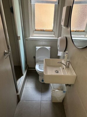 A small bathroom with a toilet, sink, and hand sanitizer dispenser. - 5 minutes to Central Sydney - Lord Raglan Hotel (Alexandria)