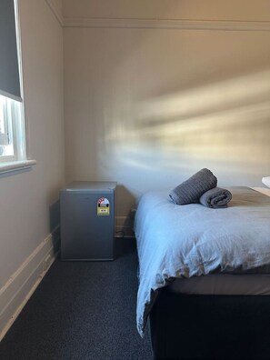 A hotel room with a bed, a small heater, and a window. - 5 minutes to Central Sydney - Lord Raglan Hotel (Alexandria)