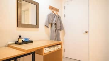 Une salle de bain avec un meuble-lavabo en bois, un miroir, un porte-serviettes avec une serviette et une porte.