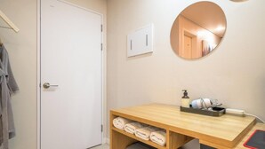 A bathroom with a wooden vanity, a mirror, a towel rack, and a wall-mounted air conditioning unit. - Suwon Hash Hotel (Suwon)