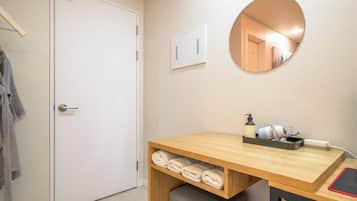 Uma casa de banho com toucador de madeira, espelho, porta-toalhas e unidade de ar condicionado na parede.