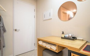 A bathroom with a wooden vanity, a mirror, a towel rack, and a wall-mounted air conditioning unit. - Suwon Hash Hotel (Suwon)