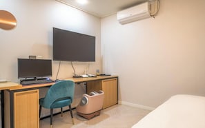 A hotel room with a desk, two monitors, a chair, a bed, an air conditioning unit, and a waste bin. - Suwon Hash Hotel (Suwon)