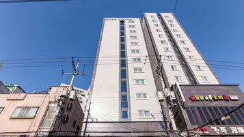A high-rise building with multiple floors, a prominent sign at the top, and various utility poles and wires.