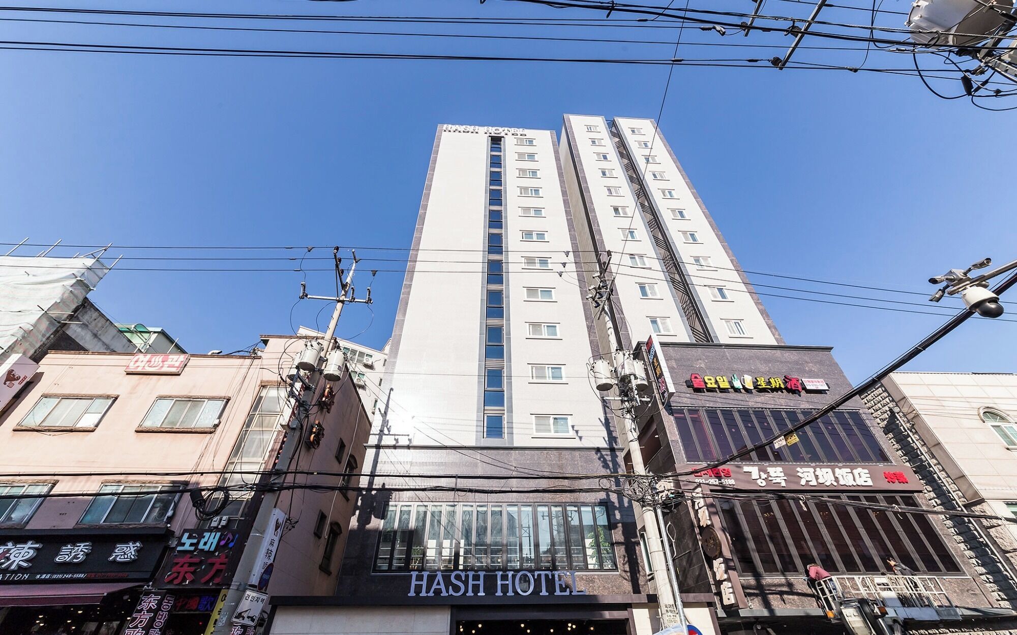 A multi-story building with a prominent sign for 'HASH HOTEL' at the top.