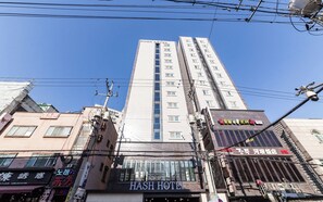 Un edificio a più piani con un cartello ben visibile che riporta 'HASH HOTEL'.