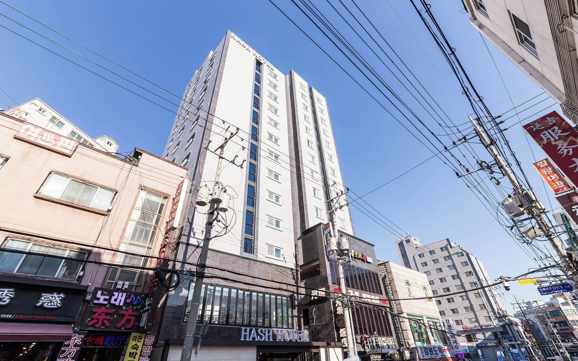 A multi-story building with a prominent sign for 'HASH HOTEL' on the ground floor.