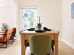 En matplats med ett träbord, stolar och ett fönster med utsikt över träd.