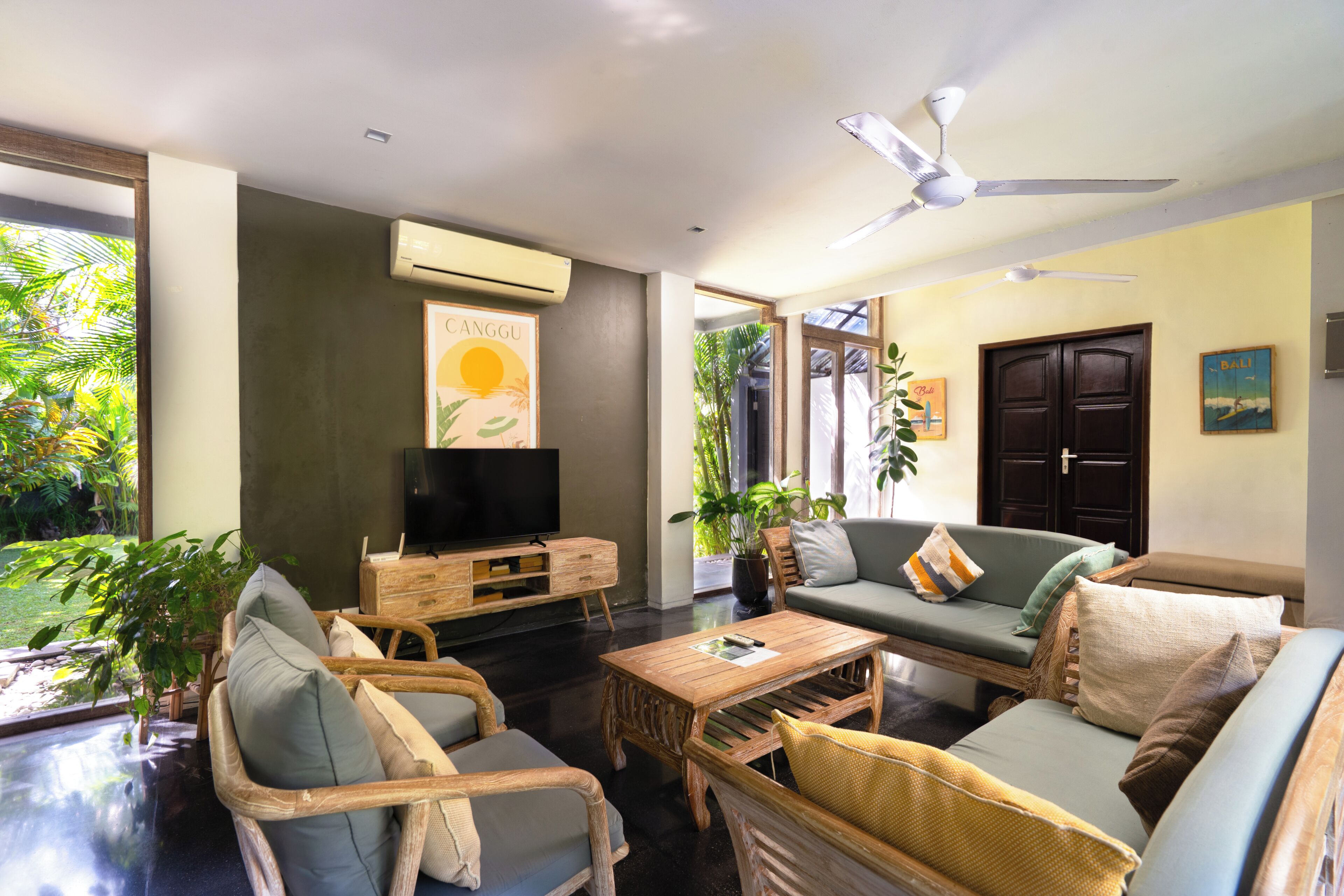 A living room with a television, sofa, chairs, a coffee table, and a ceiling fan.